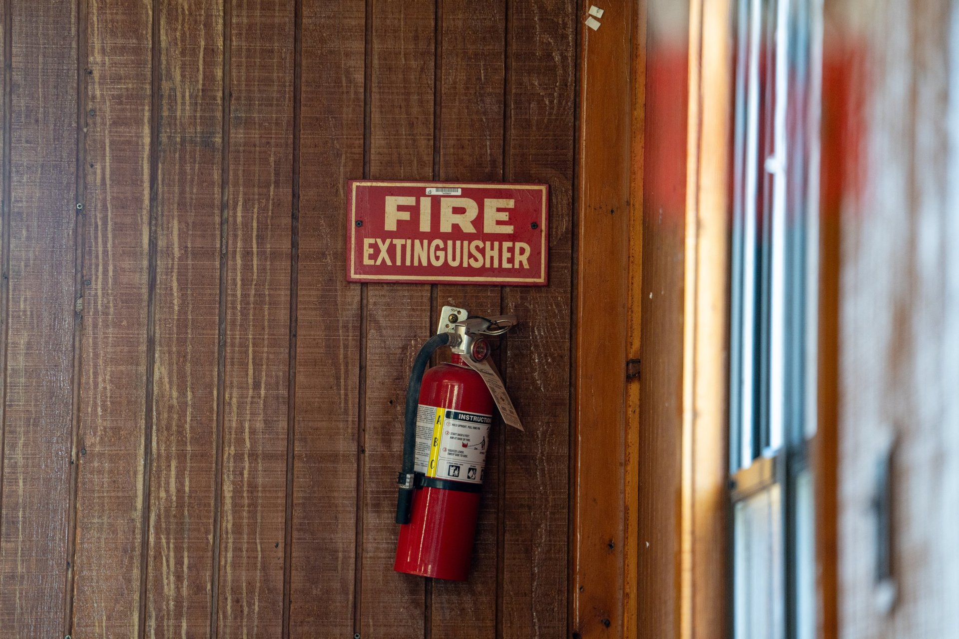 A fire extinguisher is hanging on a wooden wall with safety sign